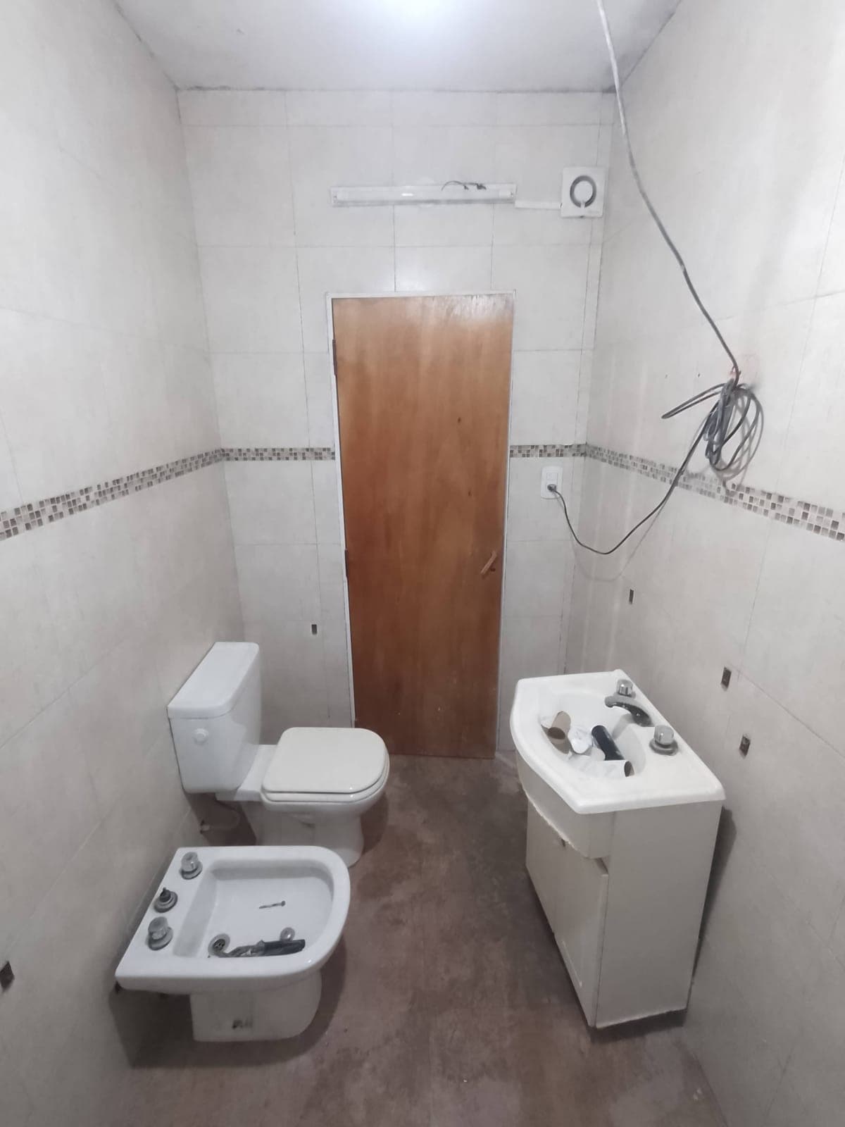 Baño terminado con inodoro, lavatorio y puerta de madera