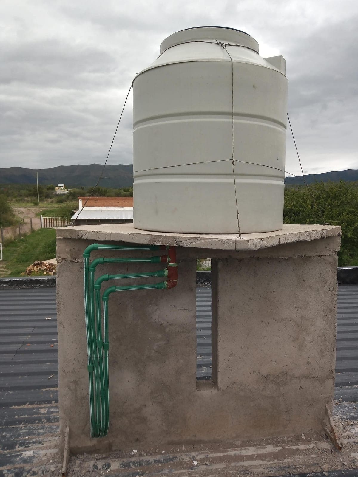 Tanque de agua sobre torre con conexiones nuevas, con las sierras de fondo